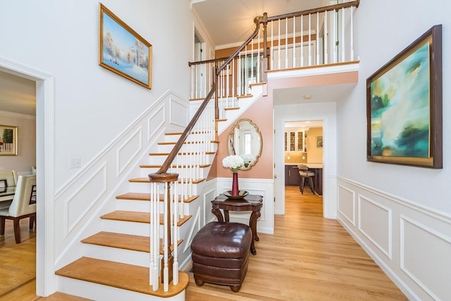 113 Sparrow Rd, Stoughton, MA 02072 - stairs featuring ornamental molding, a decorative wall, a wainscoted wall, and wood finished floors