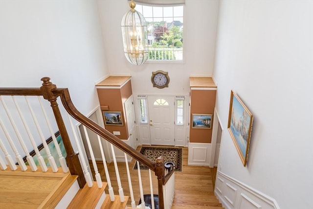 113 Sparrow Rd, Stoughton, MA 02072 - foyer entrance featuring a decorative wall, light wood-style flooring, a high ceiling, a chandelier, and a wainscoted wall