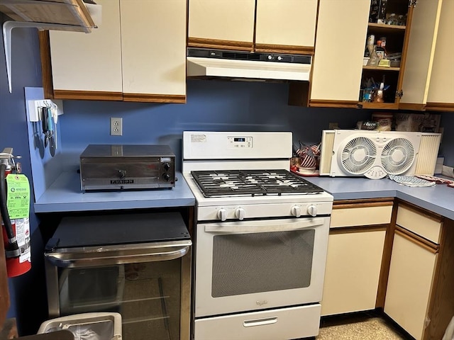 kitchen with white range with gas stovetop, a toaster, dark countertops, and under cabinet range hood