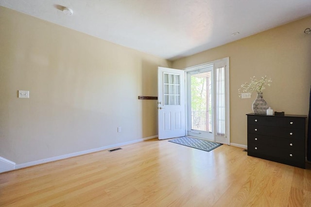 entrance foyer with baseboards, wood finished floors, and visible vents