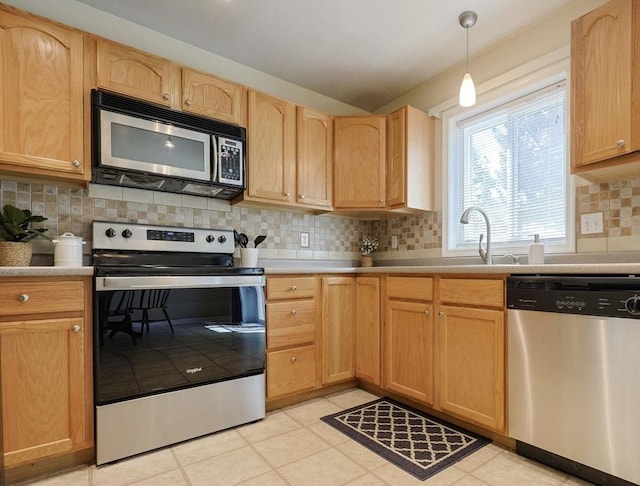 kitchen featuring light brown cabinetry, tasteful backsplash, light countertops, a sink, and stainless steel appliances