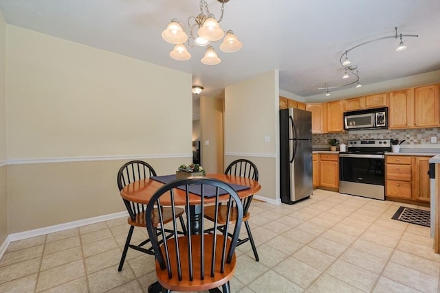 kitchen with tasteful backsplash, light countertops, baseboards, a notable chandelier, and stainless steel appliances