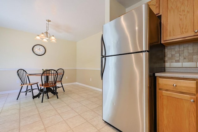 kitchen featuring freestanding refrigerator, baseboards, decorative backsplash, and light countertops