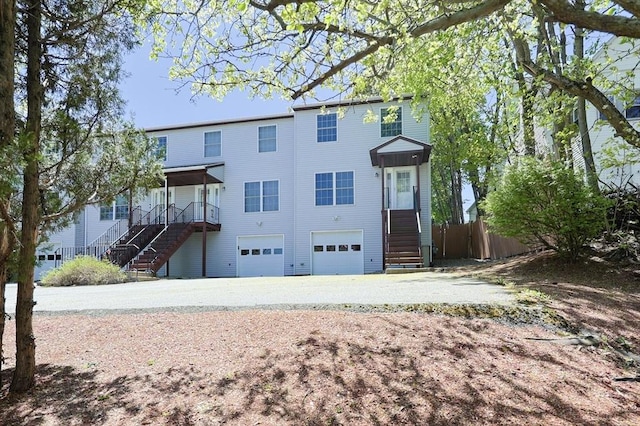 view of front of property featuring stairs, a garage, fence, and concrete driveway