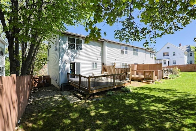 back of property with a fenced backyard, a wooden deck, and a yard