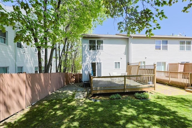 rear view of house featuring a fenced backyard, a yard, and a deck