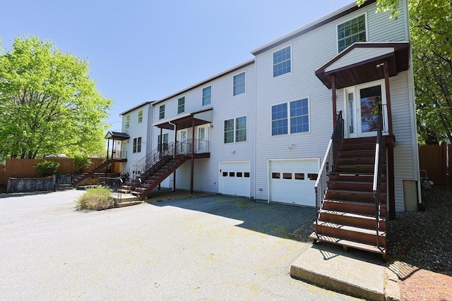 back of house with an attached garage, fence, stairs, and driveway