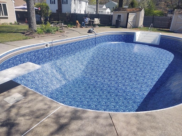 view of swimming pool featuring an outdoor structure, a storage unit, a fenced backyard, and a patio