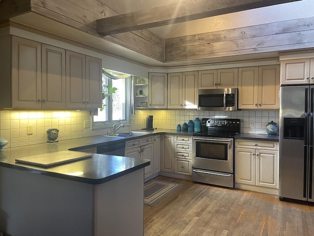 kitchen with lofted ceiling, light wood-style flooring, a peninsula, stainless steel appliances, and a sink