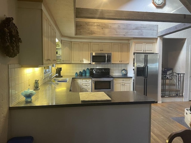 kitchen featuring decorative backsplash, appliances with stainless steel finishes, a peninsula, light wood-style floors, and a sink