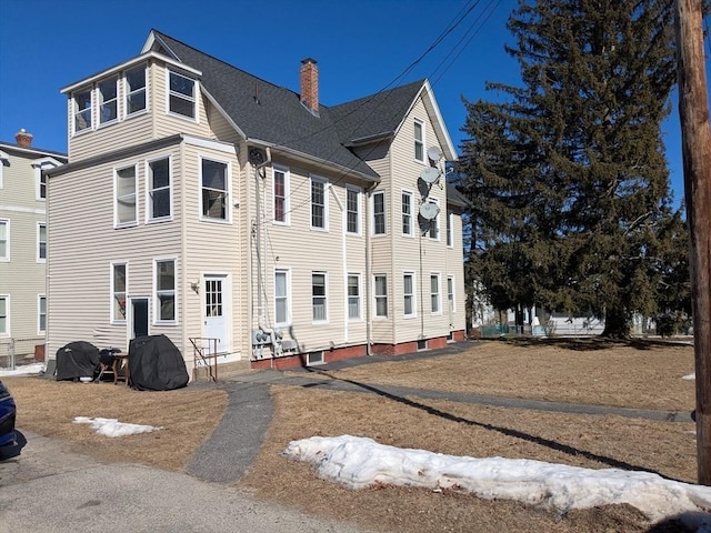 exterior space featuring roof with shingles and a chimney