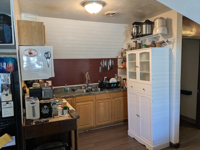 kitchen with lofted ceiling, dark countertops, visible vents, dark wood-type flooring, and a sink