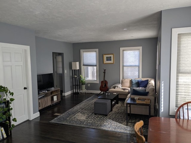 living area with a healthy amount of sunlight, a textured ceiling, baseboards, and wood finished floors