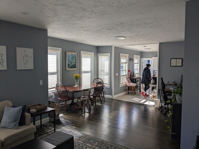 living area with a textured ceiling, baseboards, and wood finished floors