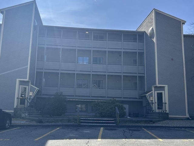 view of building exterior with entry steps and uncovered parking