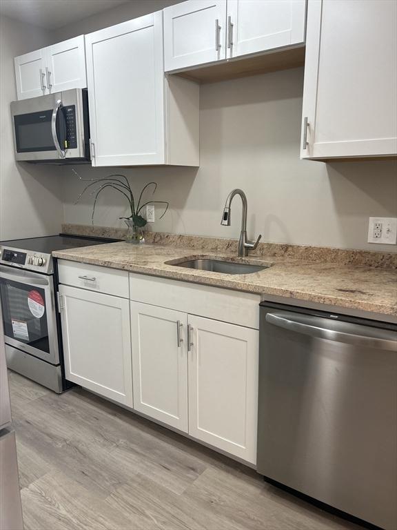 kitchen featuring a sink, stainless steel appliances, white cabinets, and light wood finished floors