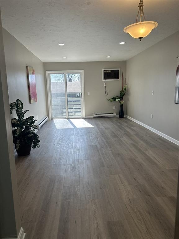 interior space featuring a wall unit AC, baseboards, dark wood finished floors, recessed lighting, and baseboard heating