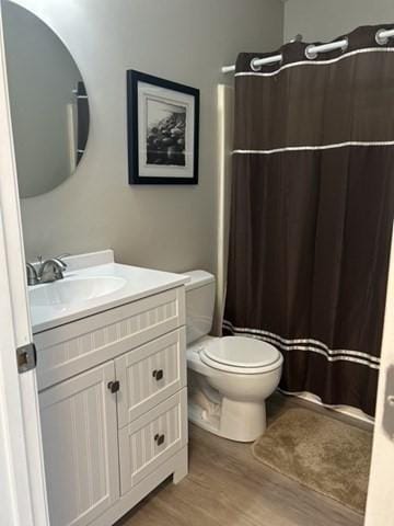 bathroom featuring a shower with shower curtain, toilet, vanity, and wood finished floors