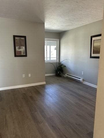 spare room with baseboards, dark wood-style flooring, baseboard heating, and a textured ceiling