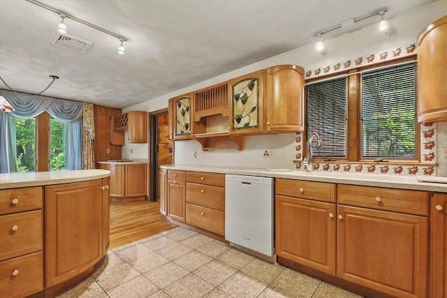210 Plain Dr, Stoughton, MA 02072 - kitchen featuring white dishwasher, track lighting, light tile patterned floors, light countertops, and brown cabinets