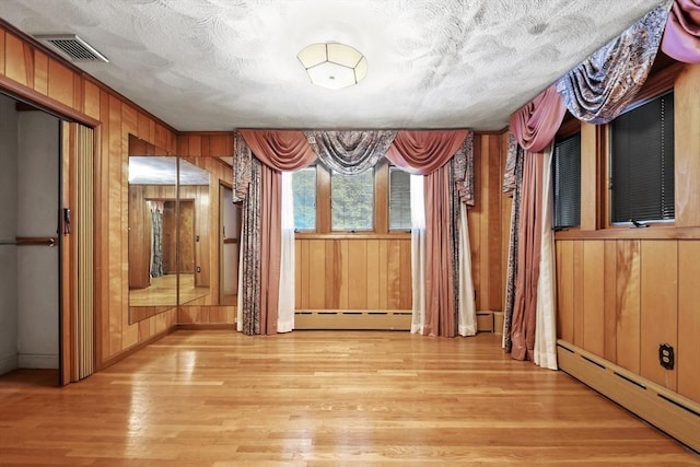 210 Plain Dr, Stoughton, MA 02072 - unfurnished dining area with a baseboard heating unit, light wood-style floors, and wood walls