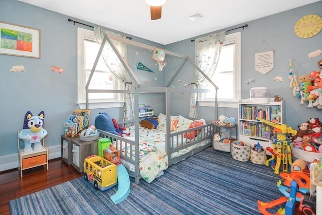 bedroom with visible vents, multiple windows, a ceiling fan, and wood finished floors