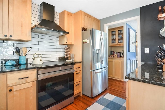 kitchen with dark wood-type flooring, light brown cabinetry, backsplash, appliances with stainless steel finishes, and wall chimney exhaust hood