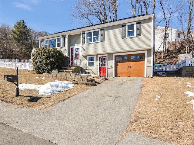 raised ranch with fence, a garage, and driveway