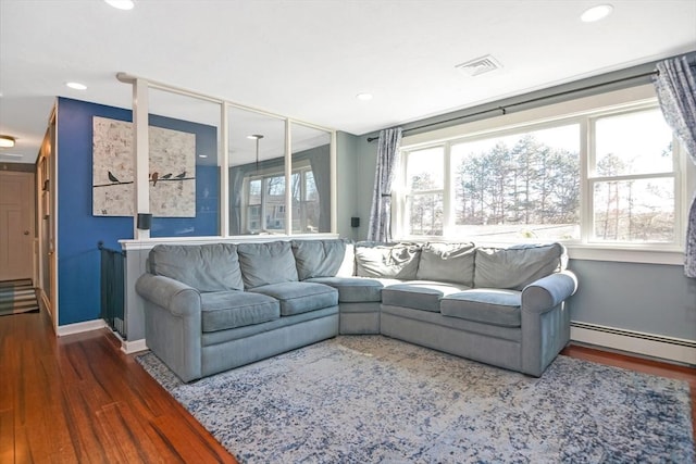 living area featuring visible vents, baseboard heating, baseboards, and wood finished floors