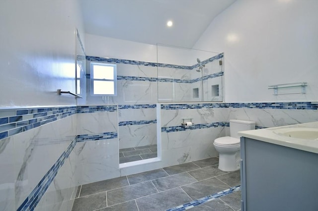 bathroom featuring tile walls, a tile shower, toilet, vanity, and recessed lighting