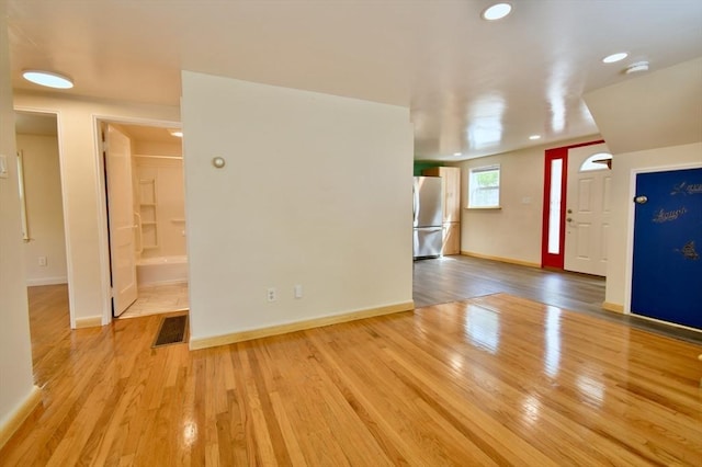 empty room featuring wood finished floors, recessed lighting, baseboards, and a smoke detector