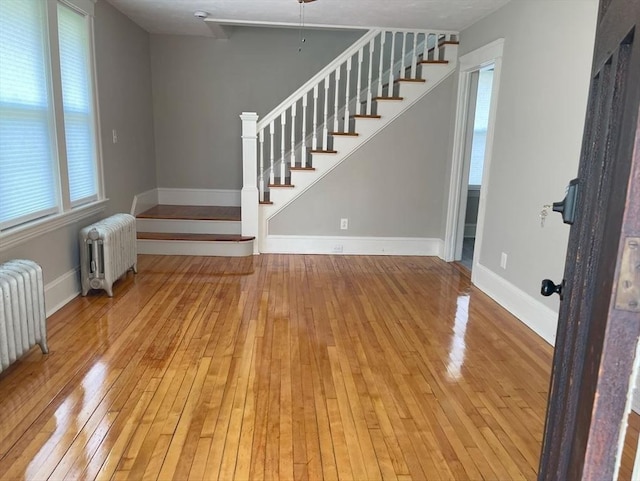 39 Barnard Rd, Worcester, MA 01605 - unfurnished living room with radiator heating unit, wood-type flooring, and stairs