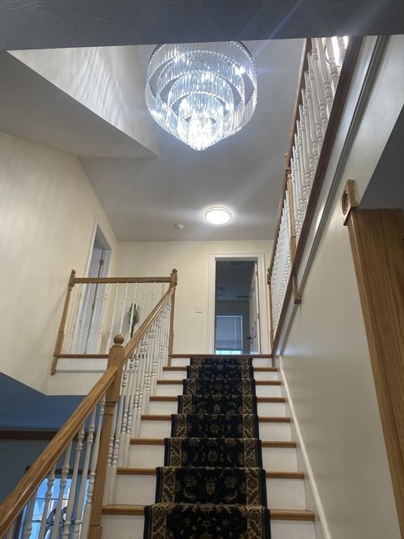 staircase with a notable chandelier