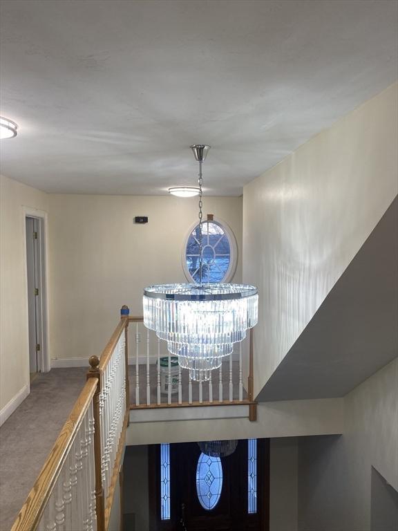 interior space featuring baseboards, a notable chandelier, and carpet flooring