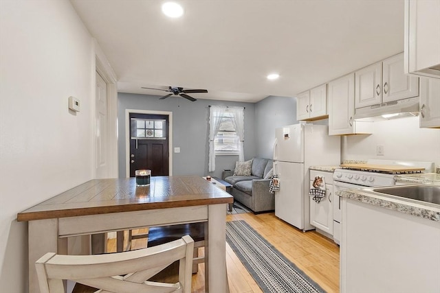 18 Doyle St, Lawrence, MA 01841 - kitchen with under cabinet range hood, ceiling fan, light wood finished floors, white cabinets, and white appliances