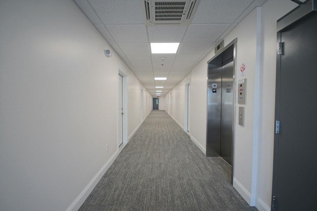 hall featuring a paneled ceiling, carpet flooring, visible vents, and elevator