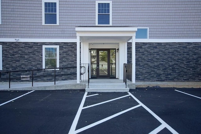 view of exterior entry with stone siding and uncovered parking