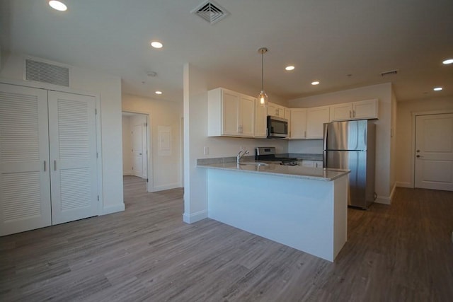 kitchen with stainless steel appliances, a peninsula, visible vents, and white cabinets