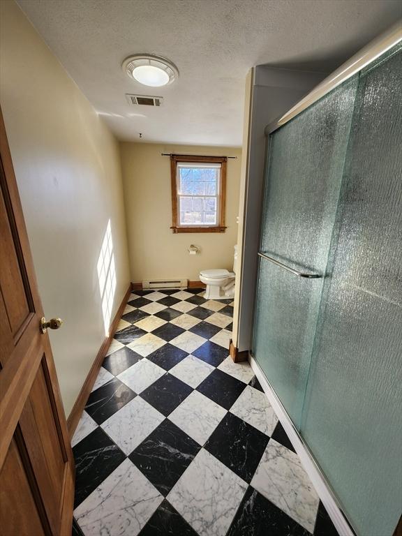 bathroom with a baseboard radiator, toilet, and an enclosed shower