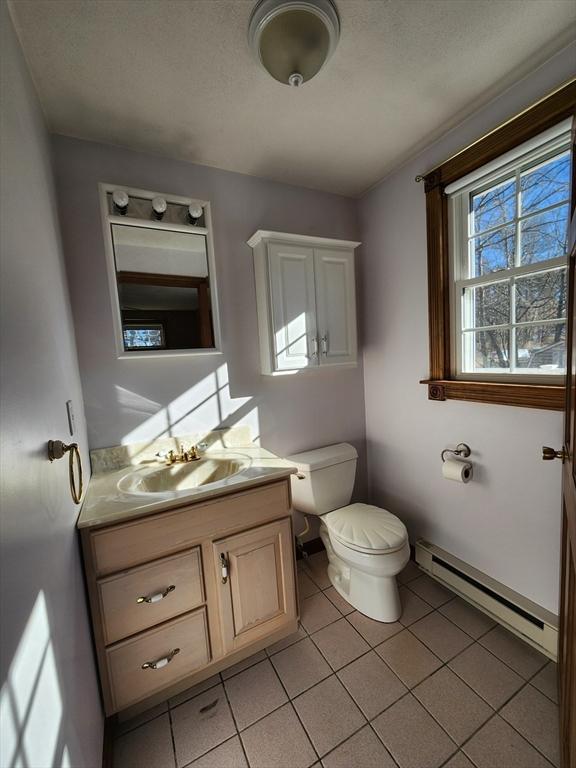 bathroom with tile patterned floors, vanity, toilet, and a baseboard radiator