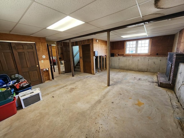 basement featuring a paneled ceiling and a brick fireplace