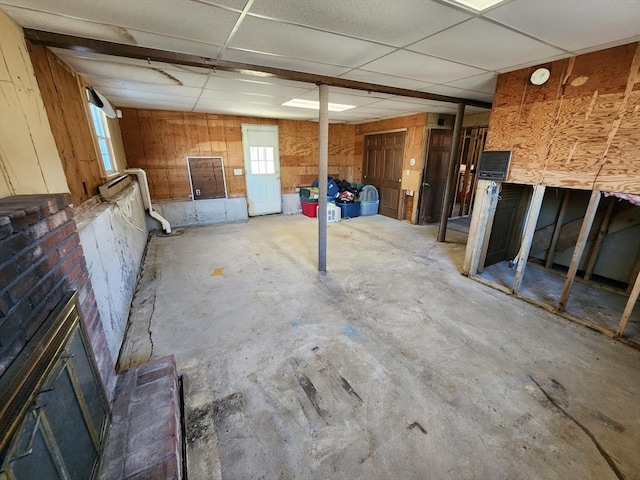 basement with a paneled ceiling and wooden walls