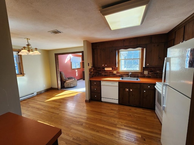 kitchen with white appliances, an inviting chandelier, sink, a baseboard radiator, and dark brown cabinets