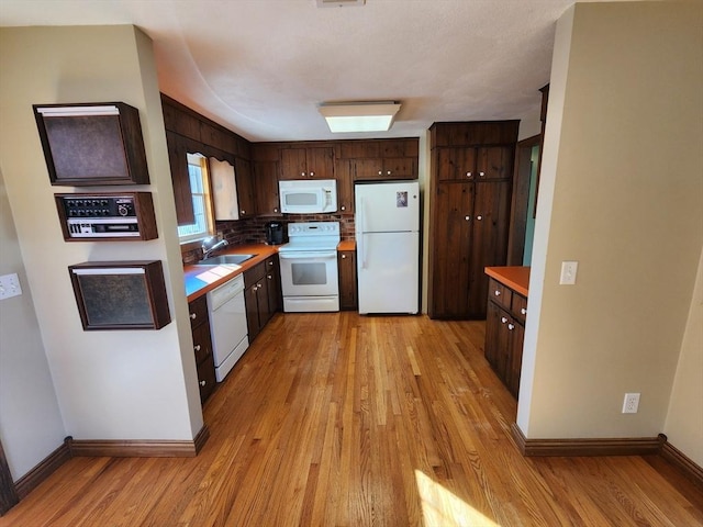 kitchen featuring white appliances, sink, tasteful backsplash, light hardwood / wood-style floors, and dark brown cabinetry