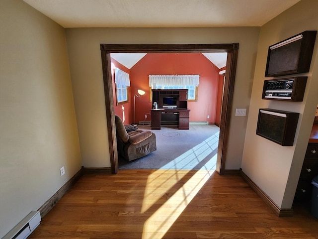 corridor with lofted ceiling, hardwood / wood-style flooring, and a baseboard heating unit