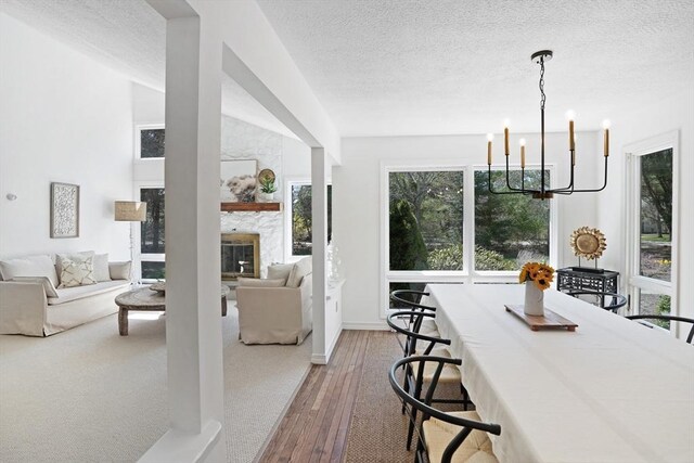 3 Down Harbor Rd, Edgartown, MA 02539 - dining space with a chandelier, a textured ceiling, a fireplace, hardwood / wood-style flooring, and baseboards