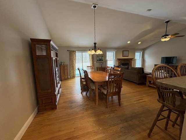 dining room featuring ceiling fan with notable chandelier, vaulted ceiling, and hardwood / wood-style floors