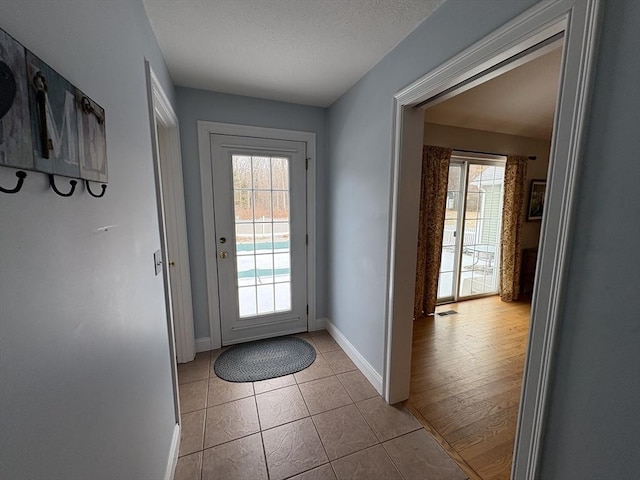 entryway featuring light tile patterned flooring, a textured ceiling, and plenty of natural light