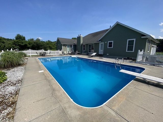 view of swimming pool featuring a patio and a diving board