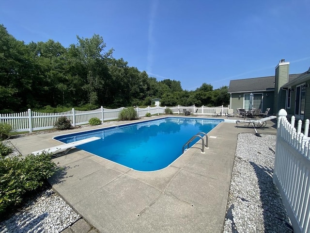 view of swimming pool with a diving board and a patio